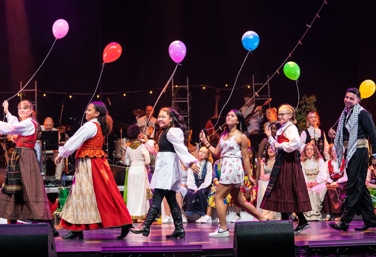 Foto av jenter i folkedrakt med hver sin ballong på forestillingen Fargespill Trondheim 10 år
